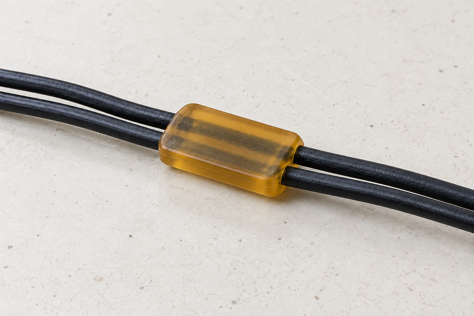 Illustrative slim amber LPM wire retainer around two parallel black cables